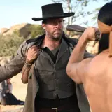Armie Hammer i vilda västern, redo för strid. En man med bandana drar vapen.