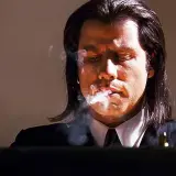 John Travolta i en ikonisk scen från filmer med John Travolta, röker och ser fundersam ut.