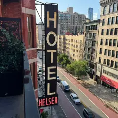 Neo-upplyst skylt för Chelsea Hotel, med en balkong med växter i förgrunden.