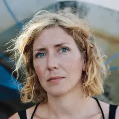 Amanda Svensson med blå ögon och blont, ostyrigt hår. Hon bär stora örhängen och tittar rakt in i kameran.