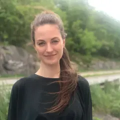 Petra Wahlgren ler mot kameran utomhus, med en grönskande bakgrund.