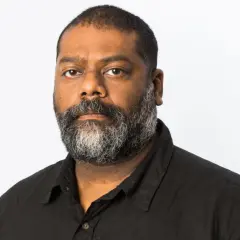 En man med skägg, baker Karim, tittar rakt fram.