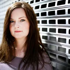 Nanna Johansson, en kvinna med brunt hår, lutar sig mot en metallgrind.