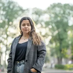 Caroline Ringskog Ferrada-Noli, partner, står utomhus i en park med träd i bakgrunden.