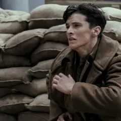 En ung soldat, en del av rollistan i Dunkirk, gömmer sig bakom sandsäckar.