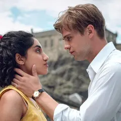 En ung kvinna med mörkt lockigt hår och en man med blont hår möts i en intensiv blick. En scen som hintar om bra miniserier.