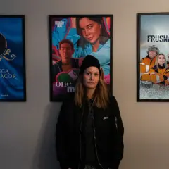 Therese Lundberg står framför tre filmaffischer: "Kungliga Kärlekssagor", "One More" och "Frusna Vägar".