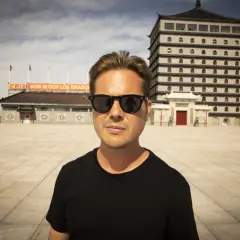 Christian Daun med solglasögon framför en asiatisk byggnad.