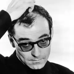 Jean-Luc Godard med handen i håret, bär glasögon och en mörk kavaj. En ikonisk bild av filmskaparen.