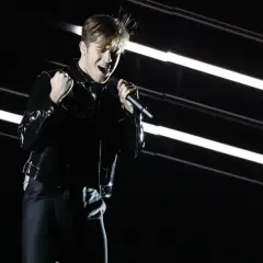 Benjamin Ingrosso levererar på scenen under Eurovision. Han sjunger passionerat med mikrofonen i handen, klädd i en glänsande svart jacka.