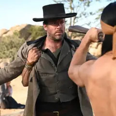 Armie Hammer i vilda västern, redo för strid. En man med bandana drar vapen.