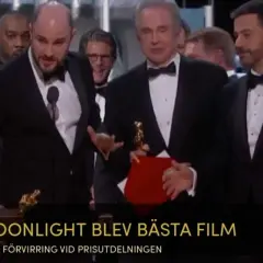 Män i kostym på scenen, en håller en Oscarstatyett och en röd mapp. Texten "MOONLIGHT BLEV BÄSTA FILM" syns.