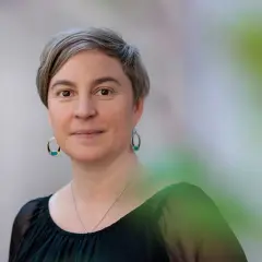 Elin Boardy, med kortklippt grått hår och ovala örhängen, ler mjukt mot kameran.