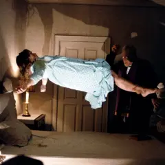En flicka svävar i luften under en exorcism. Prästen håller hennes ben, medan en annan man ser på. En ikonisk scen från rollistan i Exorcisten.