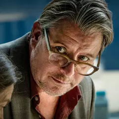 En man med glasögon lutar sig framåt, intensiv blick. En ny dansk serie på TV4.