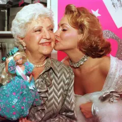 Ruth Handler, skaparen av Barbie, får en kyss av en ung kvinna. Barbie-dockan syns i bilden.