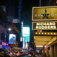 Broadway-skyltar lyser upp natten. Hamilton musikal visas på Richard Rodgers Theatre, omgivet av neonljus och trafik.