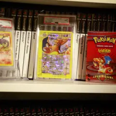 Pokémon-kort och en Pokémon-kortlek på en hylla, bland andra samlarobjekt.
