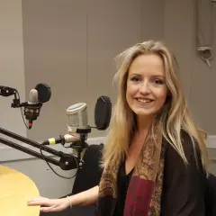 Maria Broberg ler i en radiostudio med mikrofoner och trummor i bakgrunden.
