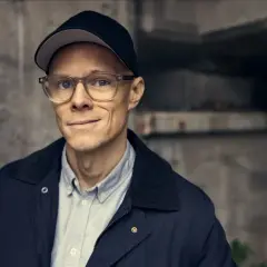 En man med glasögon och keps, redo att lösa nästa mysterium som en sann svensk deckare.