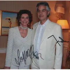Sophia Loren and Andrea Bocelli pose for a photo, both with autographs on the image.