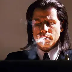 John Travolta i en ikonisk scen från filmer med John Travolta, röker och ser fundersam ut.