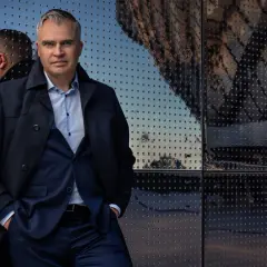 Jerker Virdborg står framför en reflekterande fasad, klädd i kostym och rock.