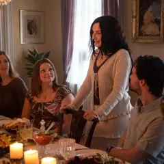 En familj samlas runt ett middagsbord, kanske för en högtidlig stund som i Knutby (tv-serie). Ljusen flimrar och maten är framdukad.