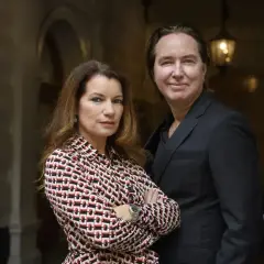 Alexander Ahndoril och en kvinna står nära varandra. Kvinnan bär en mönstrad blus och mannen en mörk kostym.