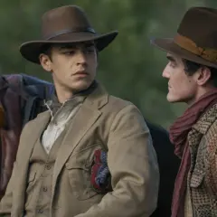 Två unga män i hattar och tidstypiska kläder, en med en sadel bredvid sig. Kanske en ung Sherlock Holmes på ett äventyr.