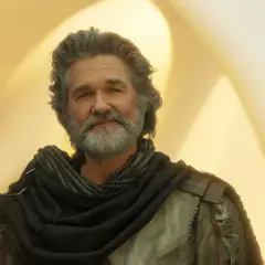 Kurt Russell med grått hår och skägg, klädd i en mörk sjal och rustning. En ikonisk skådespelare som syns i många filmer med Kurt Russell.