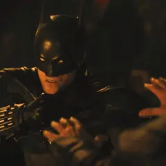 Batman i mörk dräkt, redo för strid i en av filmerna med Batman. En hand syns i förgrunden.