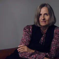 Susanna Alakoski, en svensk författare, sitter på en brun soffa med armarna korslagda.