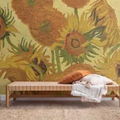 En bänk med kuddar framför en väggmålning inspirerad av Van Goghs solrosor. En vas med kvistar står till vänster.