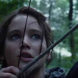 Katniss Everdeen siktar med pilbåge i skogen, en ikonisk scen från hunger games filmserie.