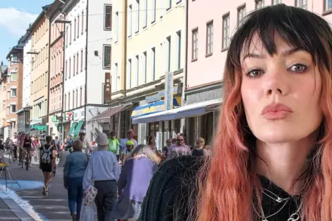 En kvinna med rosa hår poserar framför en livlig svensk stadsgata. Kanske är hon på väg att ta "little jinder expressen" till nästa äventyr.