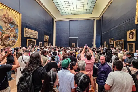 Enorm folkmassa trängs för att se Mona Lisa på Louvren. Många fotograferar med sina mobiler.