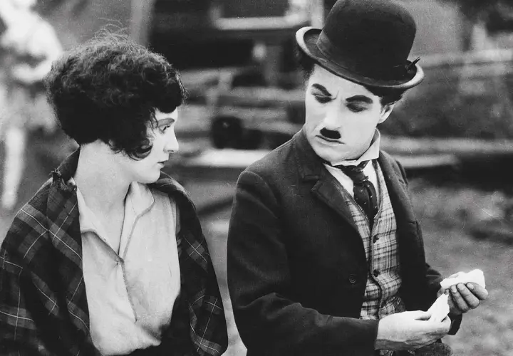 Charlie Chaplin och en kvinna i en klassisk chaplin film. Han ser bekymrad ut medan hon betraktar honom.