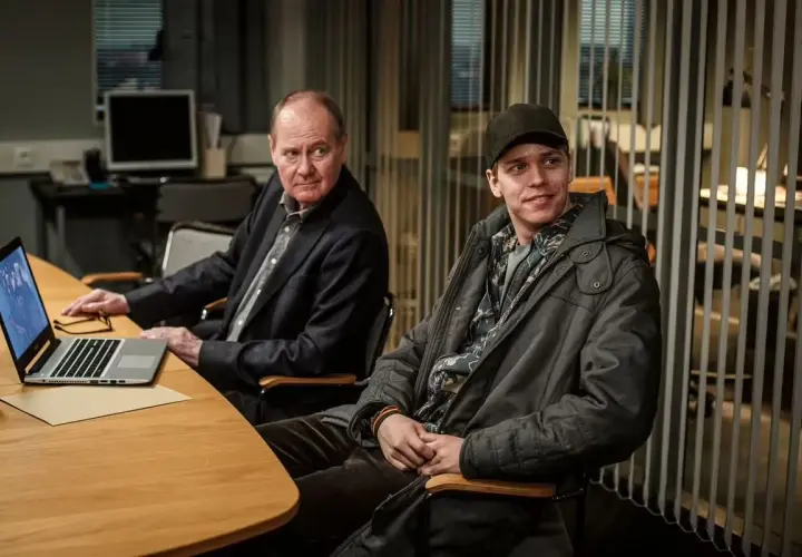 Två män vid ett bord, en äldre med laptop och en yngre med keps. Kanske planerar de nästa Beck 51-fall.