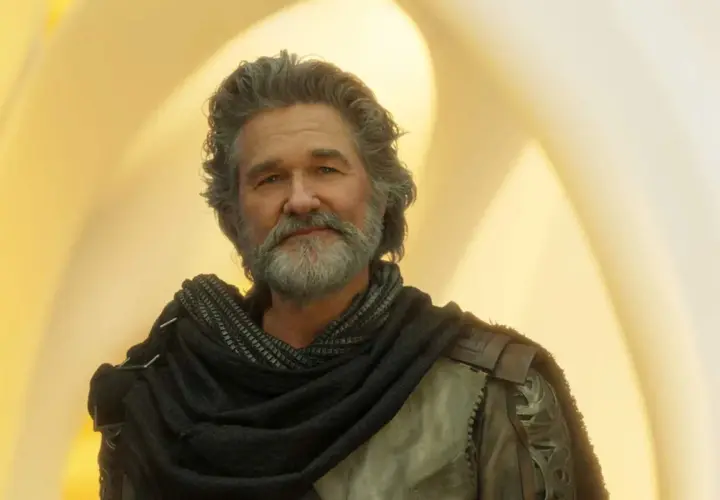 Kurt Russell med grått hår och skägg, klädd i en mörk sjal och rustning. En ikonisk skådespelare som syns i många filmer med Kurt Russell.