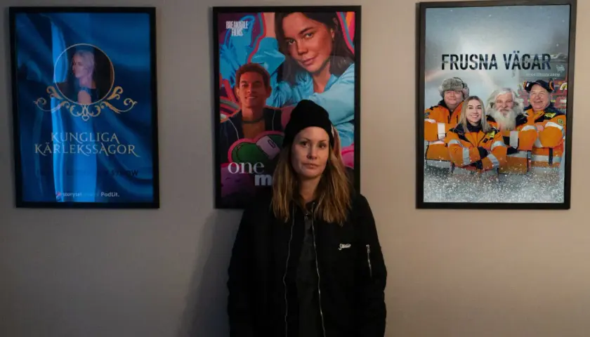 Therese Lundberg står framför tre filmaffischer: "Kungliga Kärlekssagor", "One More" och "Frusna Vägar".