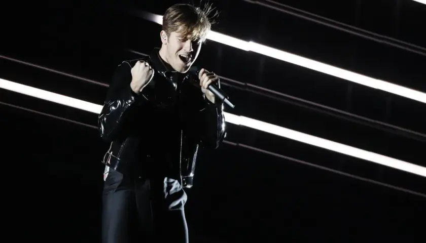 Benjamin Ingrosso levererar på scenen under Eurovision. Han sjunger passionerat med mikrofonen i handen, klädd i en glänsande svart jacka.