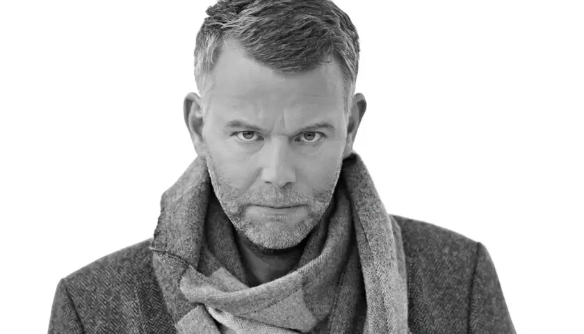 Jan Arnald, med gråmelerat hår och skägg, bär en tweedkavaj och halsduk. Kanske en scen från filmer med Jan Arnald.
