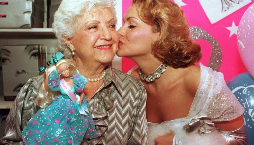 Ruth Handler, skaparen av Barbie, får en kyss av en ung kvinna. Barbie-dockan syns i bilden.