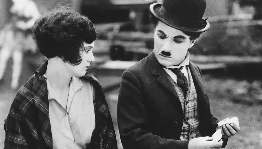 Charlie Chaplin och en kvinna i en klassisk chaplin film. Han ser bekymrad ut medan hon betraktar honom.