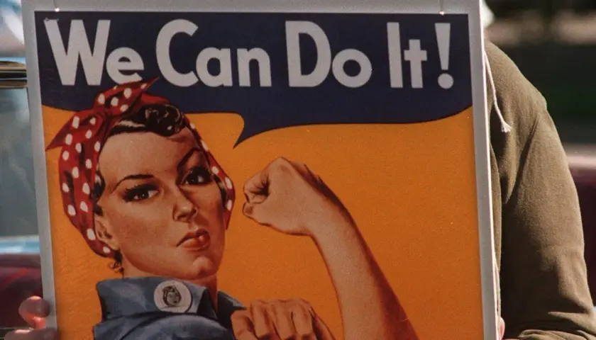 En person håller upp en affisch med Rosie the Riveter och texten "We Can Do It!". En symbol för styrka och beslutsamhet.