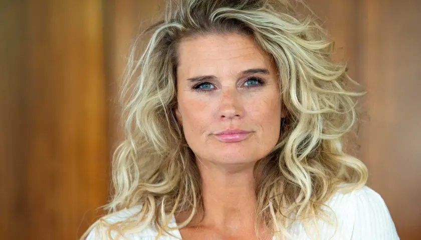 En kvinna med blont, lockigt hår och blå ögon. Hon ser lite trött ut, kanske för att det är udda veckor och mycket att göra.