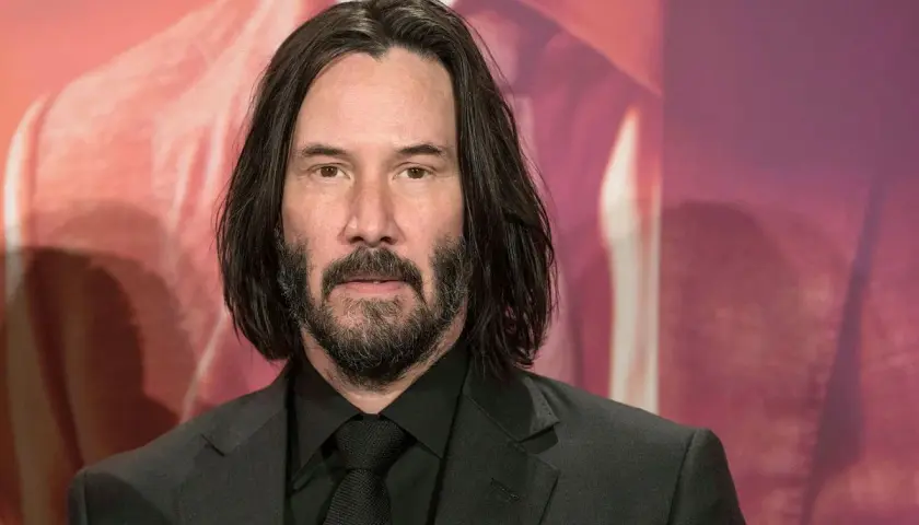 Keanu Reeves, som spelade Neo i Matrix, bär en svart kostym och slips.