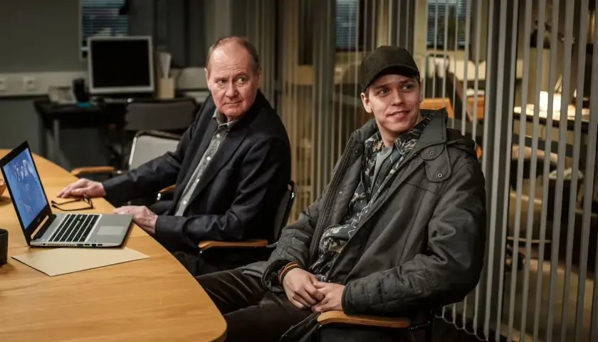 Två män vid ett bord, en äldre med laptop och en yngre med keps. Kanske planerar de nästa Beck 51-fall.