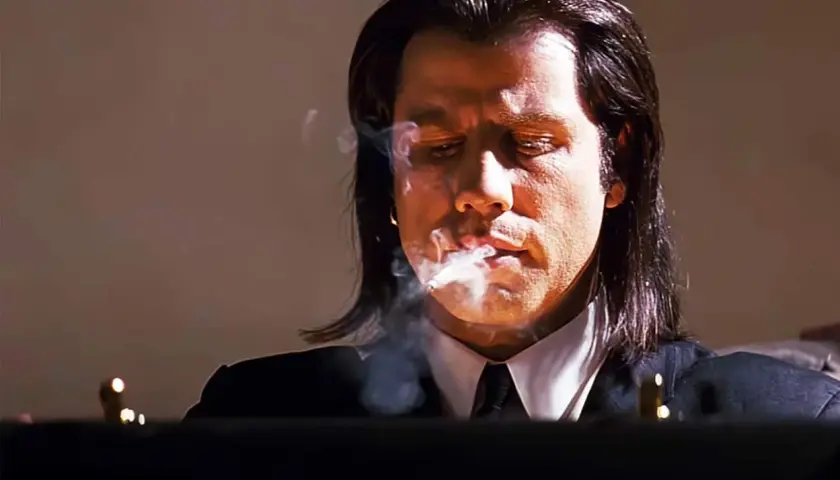 John Travolta i en ikonisk scen från filmer med John Travolta, röker och ser fundersam ut.